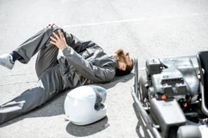 man laying on the ground next to motorcycle helmet