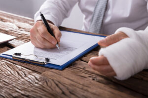 someone with a cast on their hand writing on a piece of paper